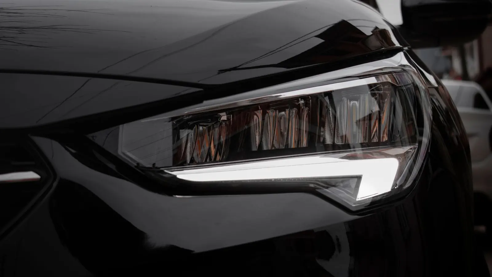 Close-up of the headlight on the front wing of a black car