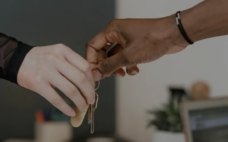 Two hands passing a set of keys across a desk