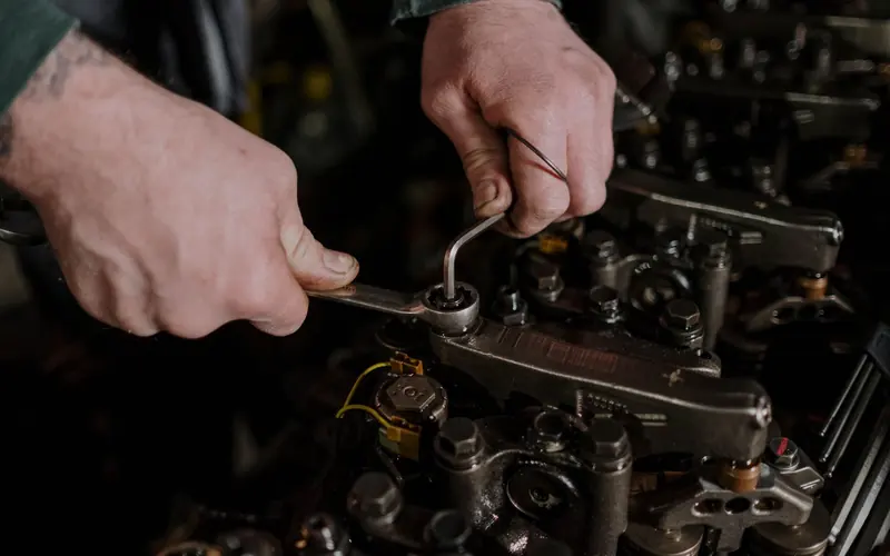 Hands using a spanner and an Allen key on an engine